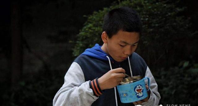 下午下课,王东端着自己的哆啦a梦饭盒在食堂外站着吃饭.