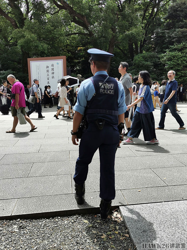 日本警察全身披挂站在路边执勤,手里拎着伸缩警棍,可以看到腰间还有