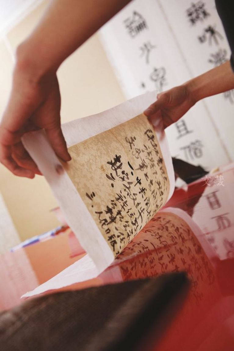 上海博物馆古画修复室：用鬃刷将宣纸裱糊在漆面的桌子上，使宣纸平整后揭起。图片来源：视觉中国