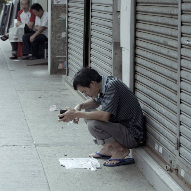香港深水埗,赛马日,蹲在路边的投注者.
