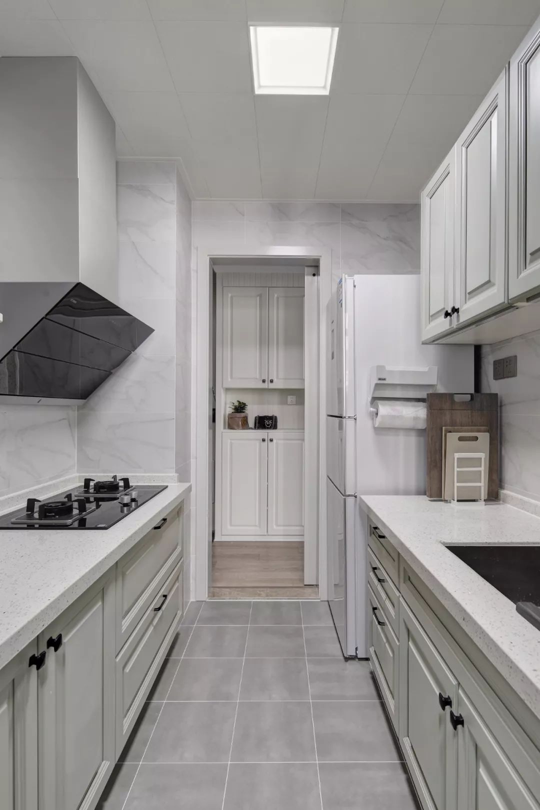 厨房地面铺设灰色哑光砖,墙面铺设大理石纹瓷砖,搭配上灰白色的
