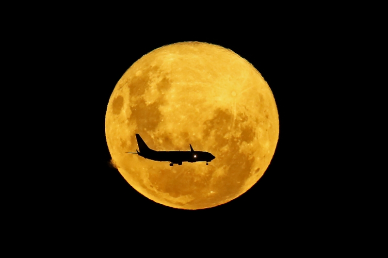 3月9日,在巴西库里蒂巴,一架客机从"超级月亮"前飞过. 新华社/法新