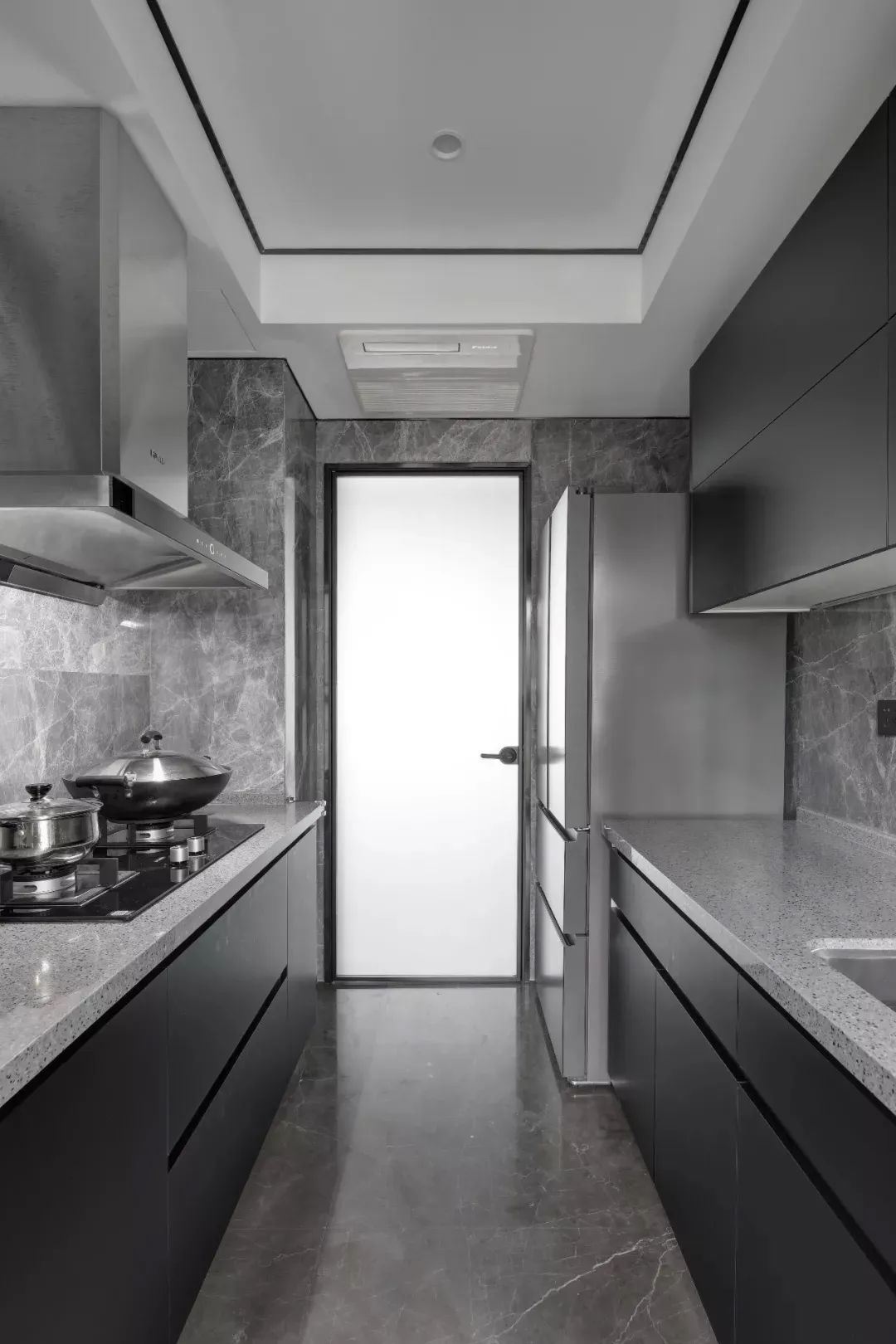 厨房以二字型的操作台布置,灰色的地面墙面与操作台,定制黑色的橱柜