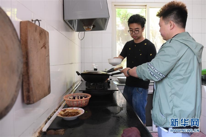 5月20日,在宁波七里屿,叶家第五代灯塔工叶超群(左)和同事叶露在厨房