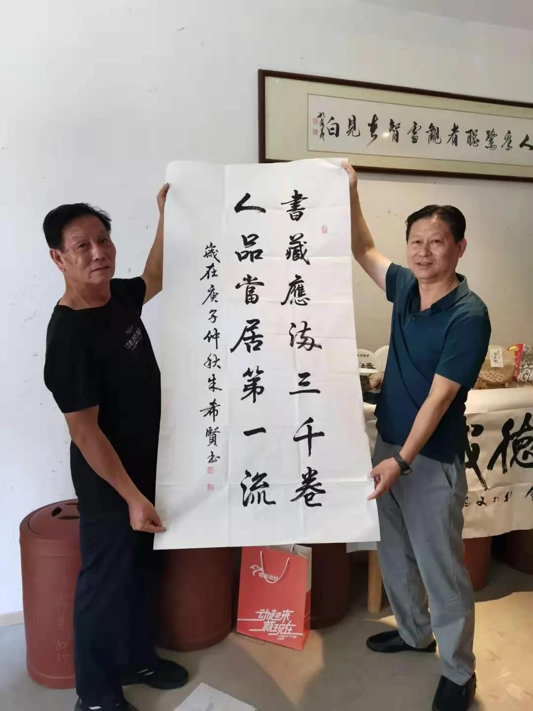 在活动上,爱心书画家朱希贤把义卖的每平尺一万六千元的"厚德载物"六