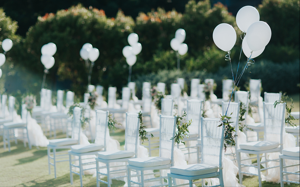 系草坪婚礼,运用绿色植物与白色纱质飘带作为椅背装饰,系上白色气球