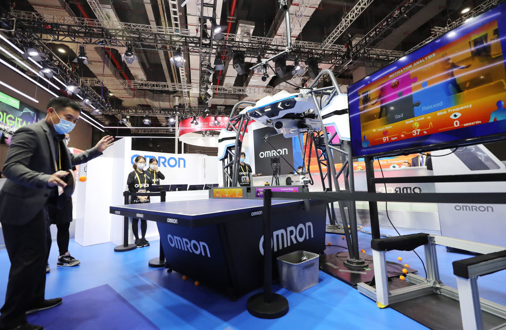 在第三届中国国际进口博览会期间，一名男子体验与欧姆龙公司的一款乒乓球教练机器人对战，右侧屏幕上实时显示他的心率和情绪指数（2020年11月5日摄）。新华社记者 方喆 摄