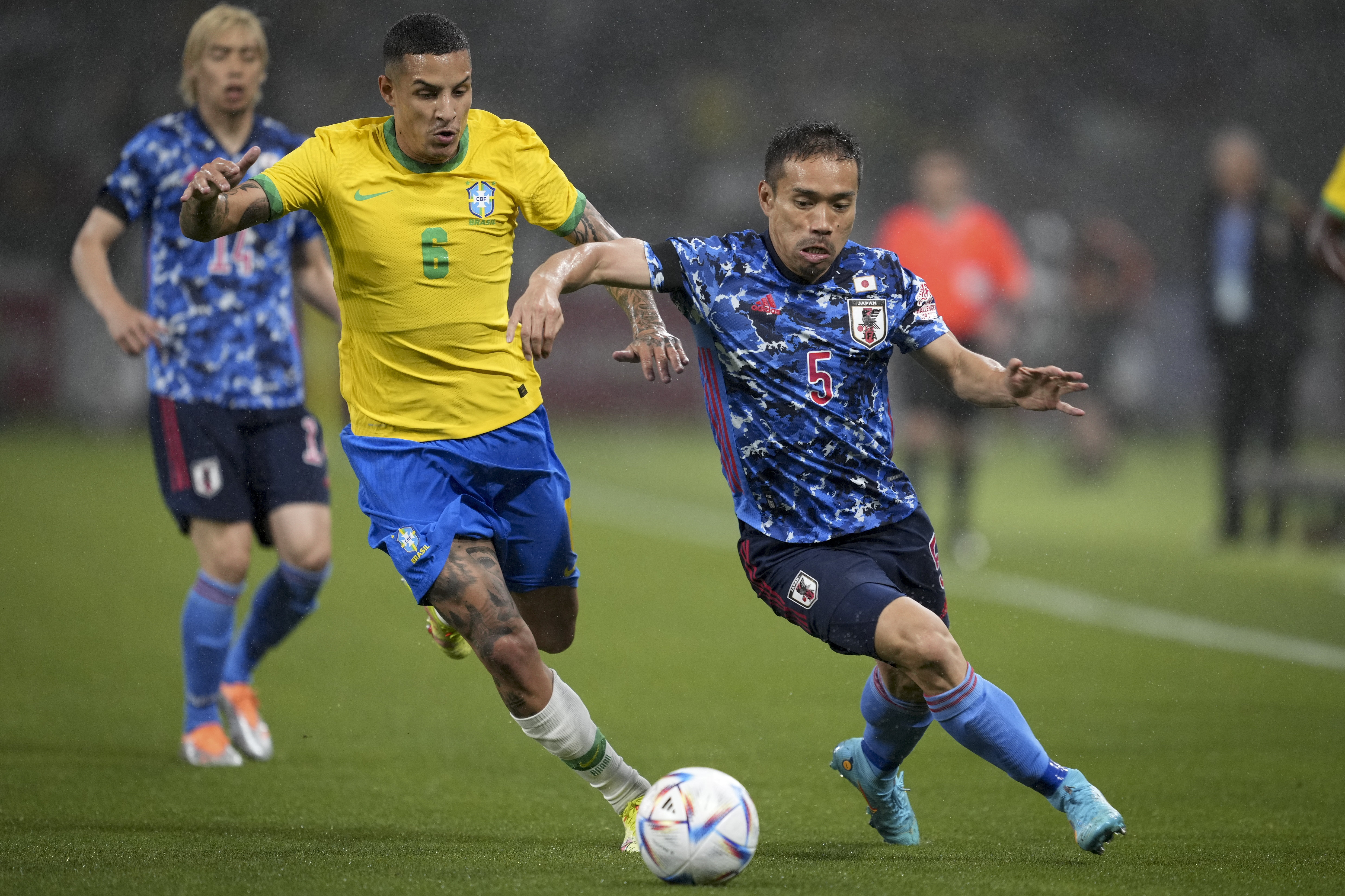 2022年6月6日，日本队球员长友佑都（右）与巴西队球员阿拉纳（中）在一场友谊赛中拼抢。