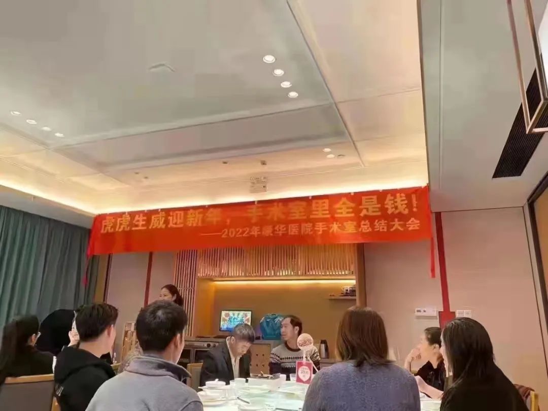 图片显示,康华医院手术室举行年终总结大会,大家围桌而坐,台上有人