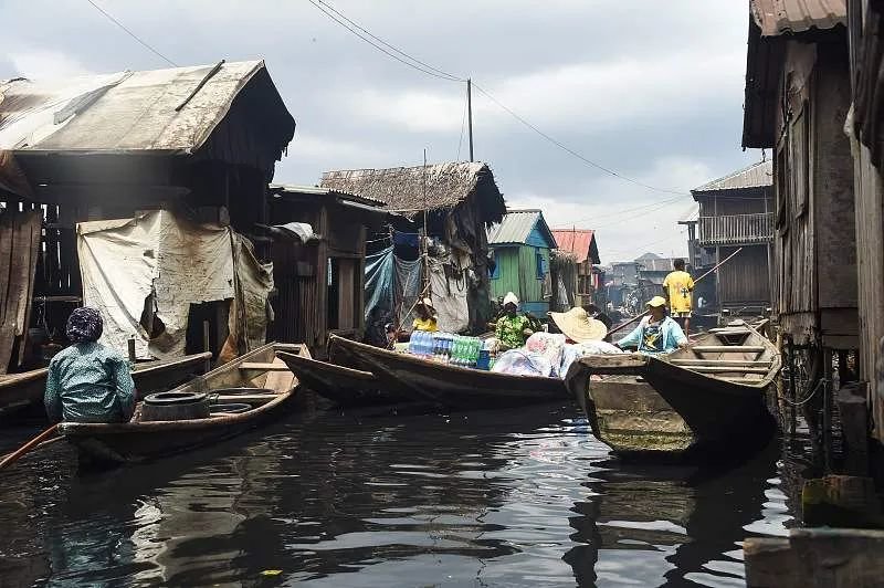 当地时间2022年10月19日，尼日利亚拉各斯，人们在贫民窟里用平底船运送货物。图/视觉中国