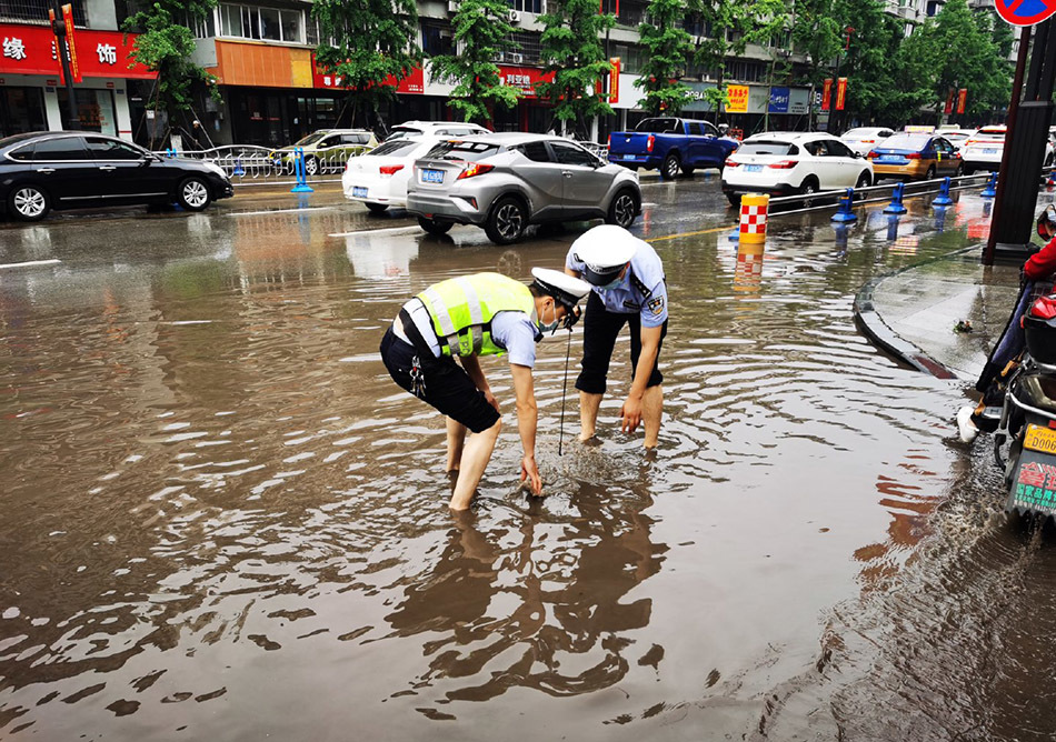 四川内江,受暴雨影响,城区街道积水严重,警察积水中打开下水道井盖,让