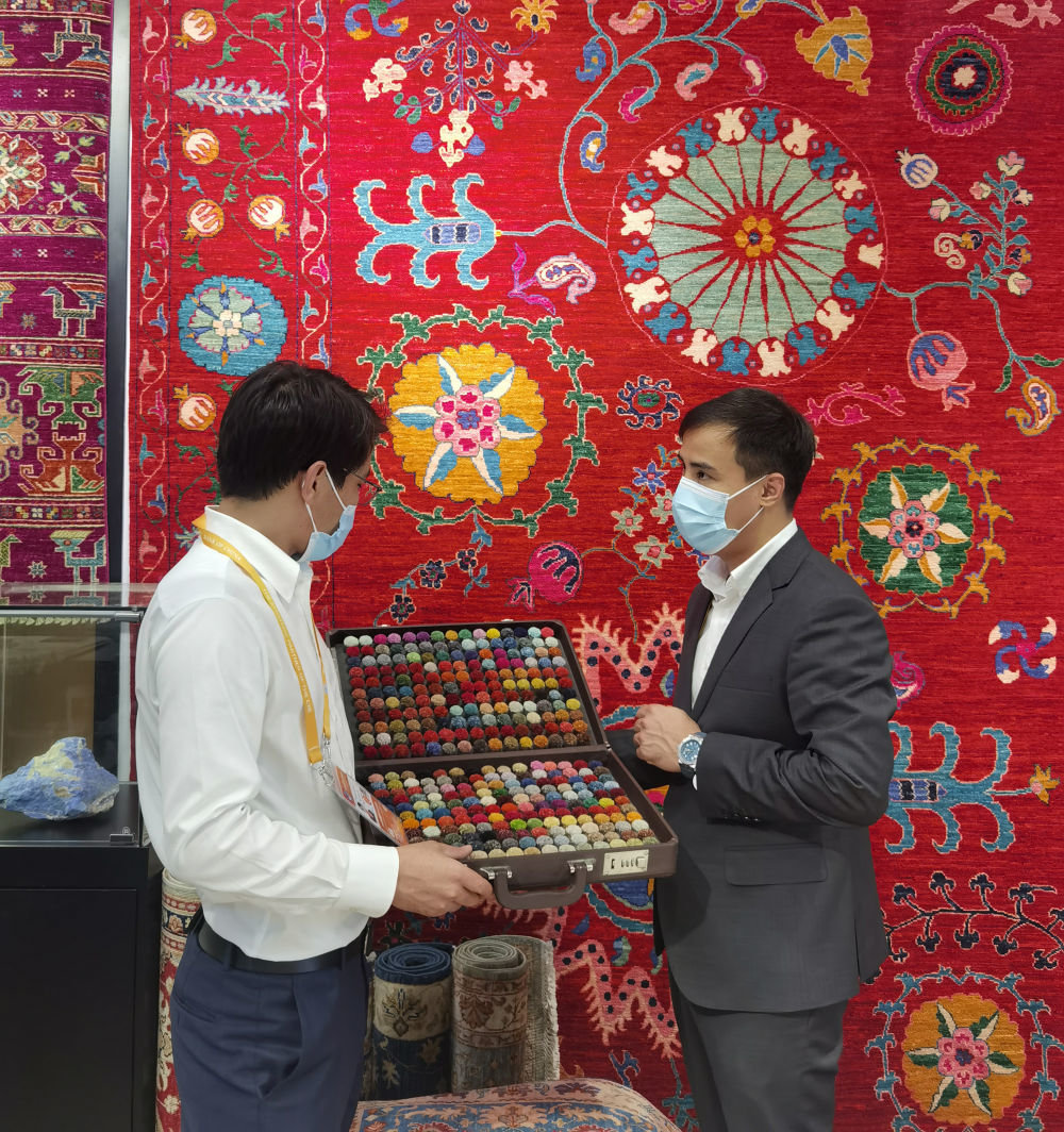 阿富汗参展商阿里·法伊兹（右）在第四届中国国际进口博览会阿富汗手工羊毛地毯展台忙碌（2021年11月5日摄）。新华社记者 吴宇 摄