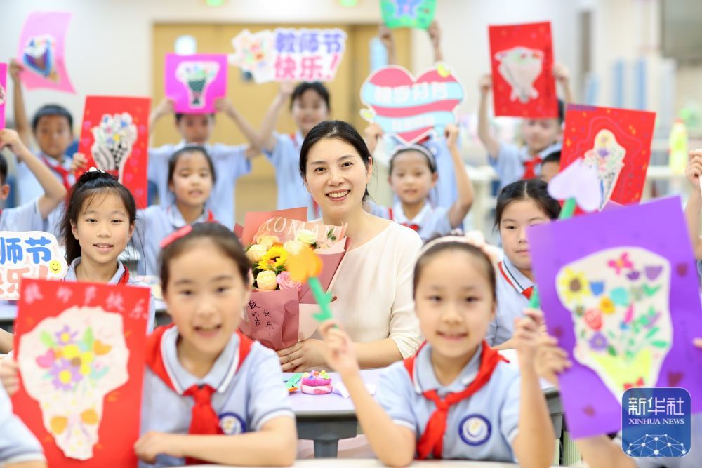 9񀙙日，在江苏省泰州市姜堰区实验小学教育集团北街北校区，学生手持手工制作的教师节贺卡和老师合影留念。新华社发（周社根摄）