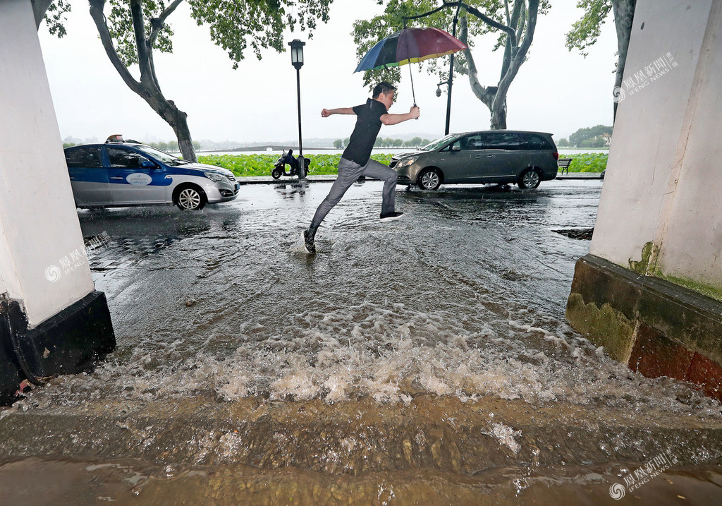 受梅雨带影响,杭州主城区下起大雨到暴雨,民众在被水淹没的道路上跳跃