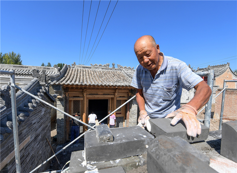 8月25日,张家口市蔚县涌泉庄乡涌泉村村民赵进忠参加村内仿古建筑的