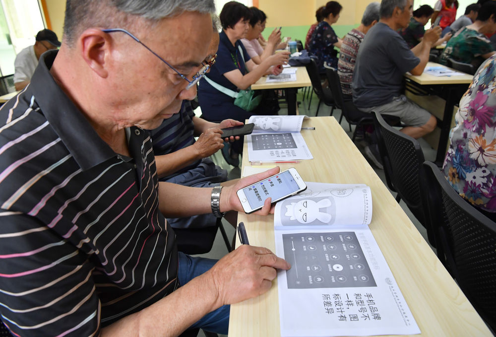 6月15日,在咸阳市小桔灯公益服务中心的教室,学员学习操作智能手机.