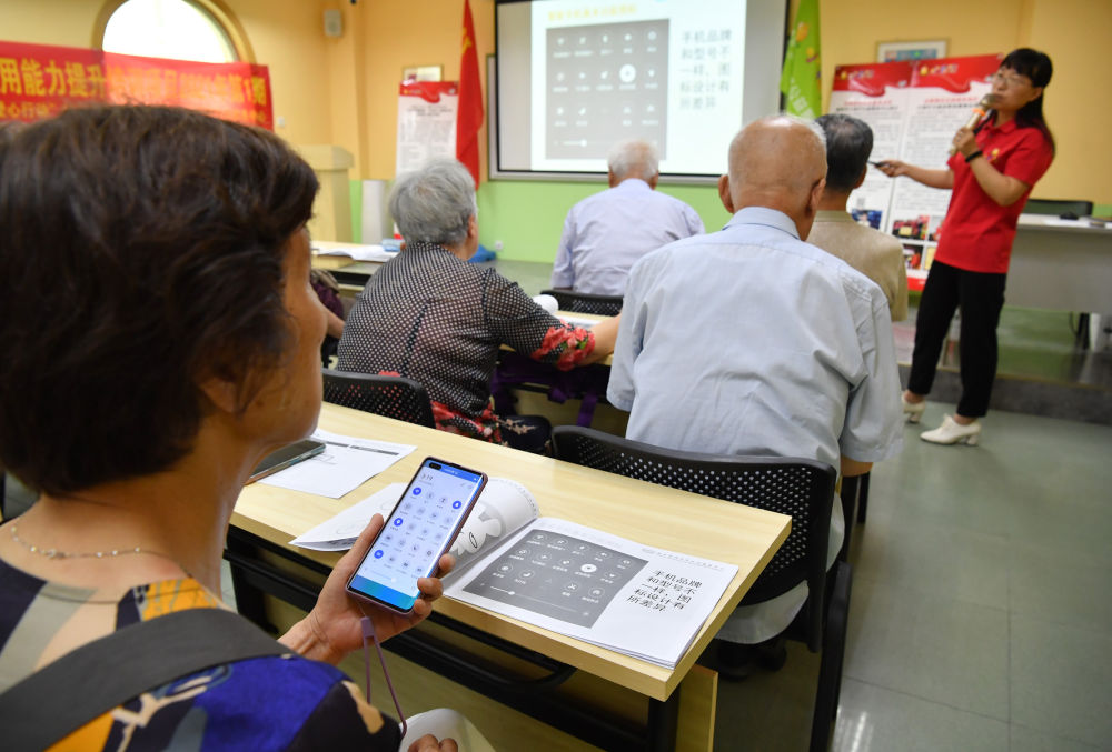 6月15日,在咸阳市小桔灯公益服务中心的教室,学员学习操作智能手机.