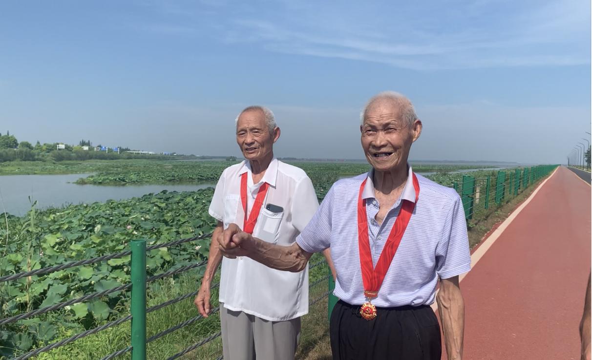 图一:红色代言人卓尚书(图左),罗仁财(图右)站在60年前亲手修筑的湖堤