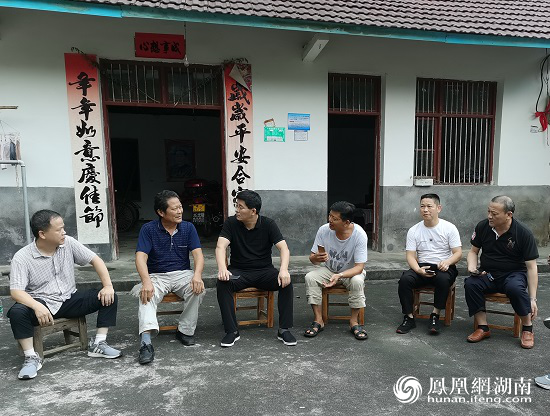 谭志华(左三)与村干部,驻村工作队在贫困户李大友家中了解情况