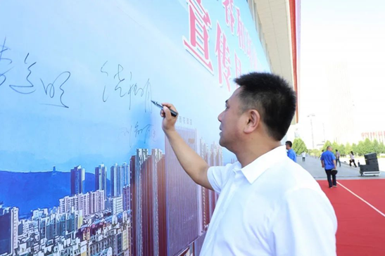 市委秘书长谢天学宣布仪式启动,出席仪式的各位领导在幕布上签名