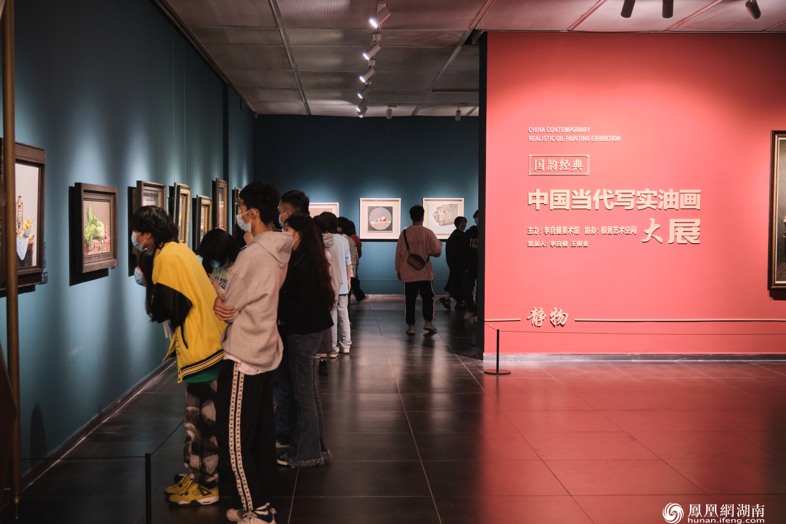 游客们认真观看展厅里的油画