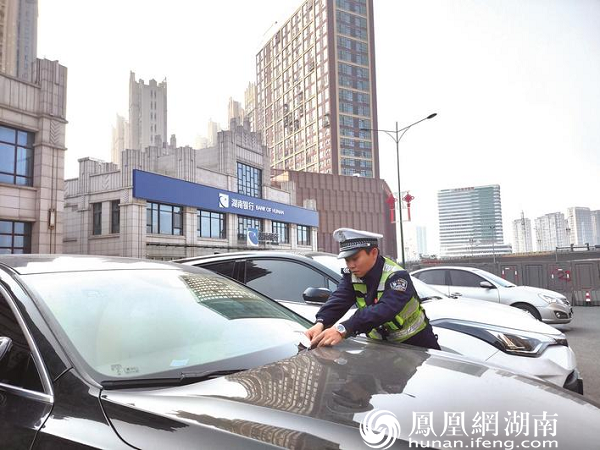 黄兴大道的东方美地营销中心门口，部分车辆停在辅道上，交警正对车辆开具罚单。宋彬彬 摄