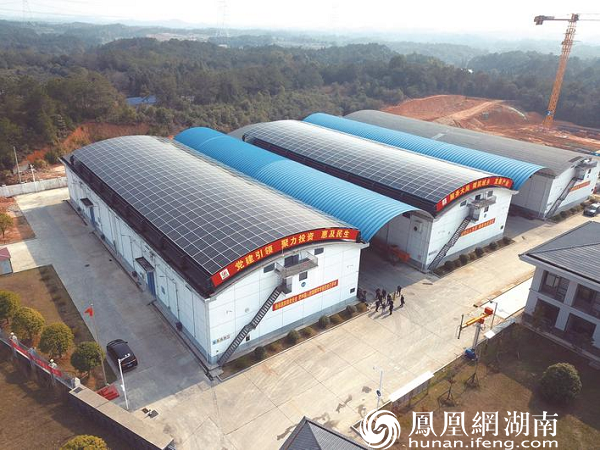 一排排光伏板在粮食仓库上方汇成一个弧形屋顶，与不远处的青山绿水相映生辉，共同造就了路口镇亮眼的“绿色风景”。胡宇韬 摄