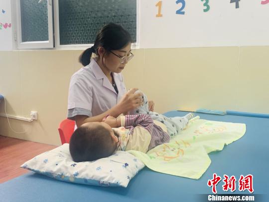 图为甘肃省康复中心医院西固合作分院治疗师正在给孩子进行按摩康复治疗，防止肌肉萎缩。　高康迪摄