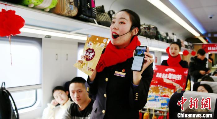 列车长杨怡如为旅客们介绍推车上的”年货“扶贫商品的种类和产地。　陶静摄