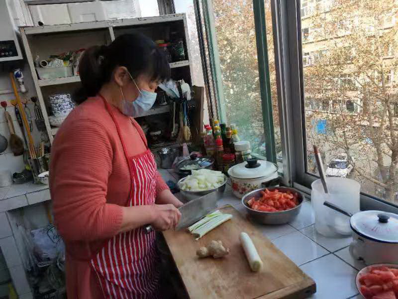 2月2日，张店区体坛小区居民王秋霞在家为社区工作人员做午饭。资料照片