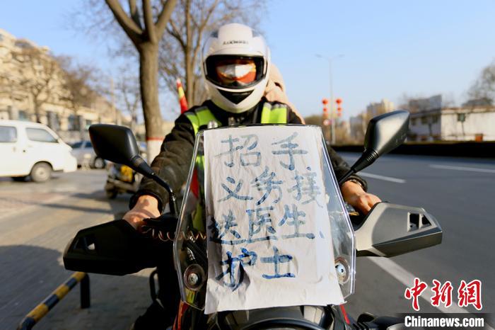 摩托车前贴着“招手义务接送医生护士”的牌子。　高展摄