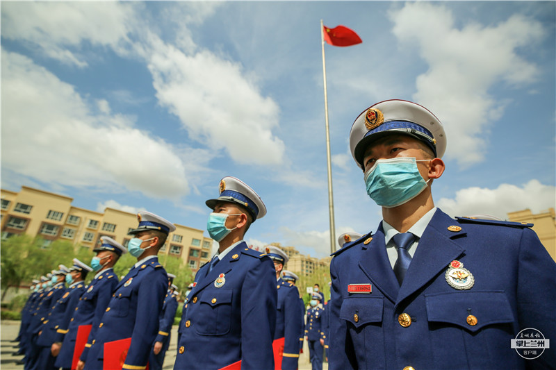 佩戴消防救援衔的新消防员在国旗下整齐列队参加仪式的消防指战员进行
