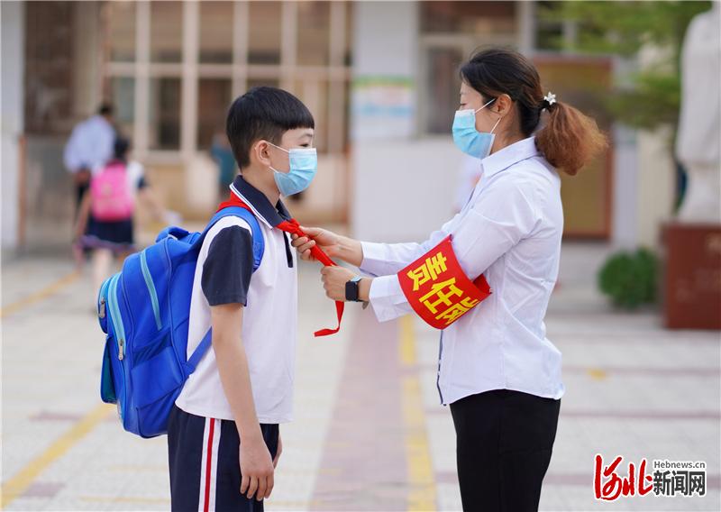 2020年6月1日,河北省邢台市内丘县实验小学,一名老师帮学生整理红领巾