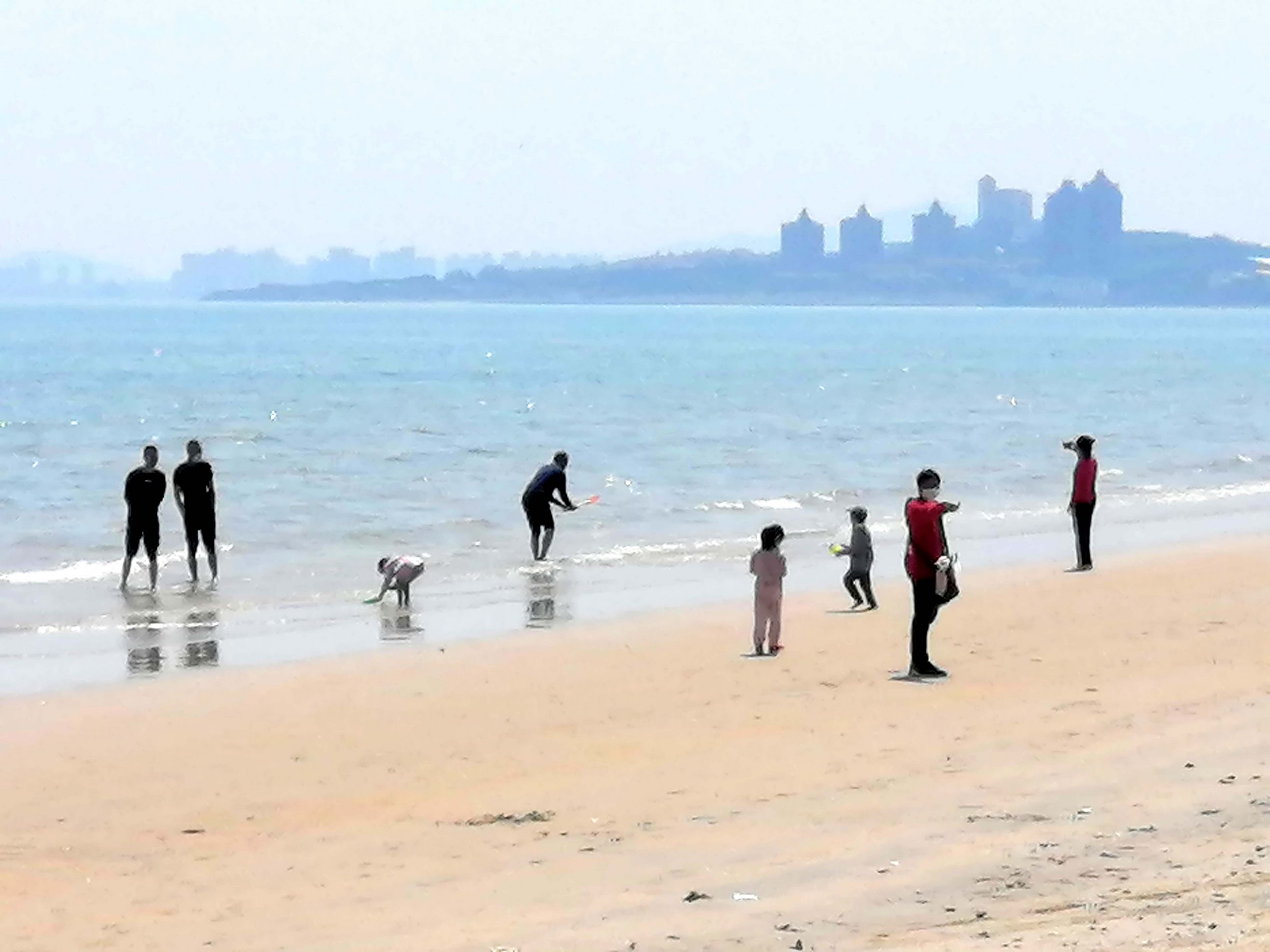 小朋友和游客在海边戏水观海,在景区游玩