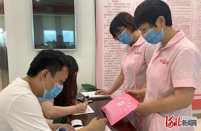 6月9日，在石家庄桥西区婚姻登记处的区妇幼保健站婚检便民点，医护人员给前来领取结婚证的一对准新人宣传免费婚检的相关知识。河北日报记者张淑会摄