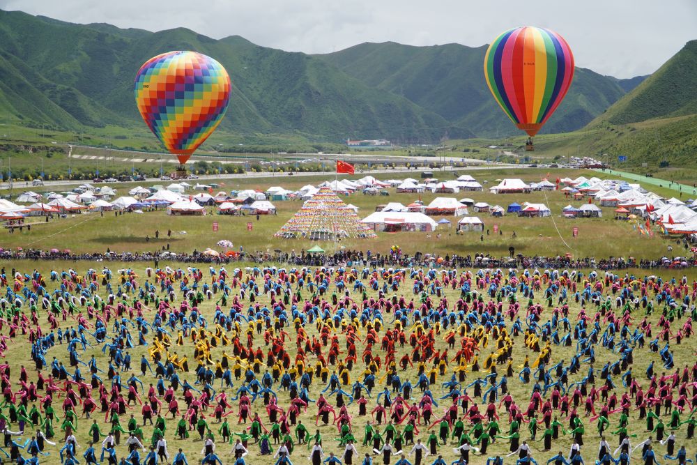 ↑8月12日，身着节日盛装的演员和当地群众在夏泽滩草原上跳起锅庄舞。