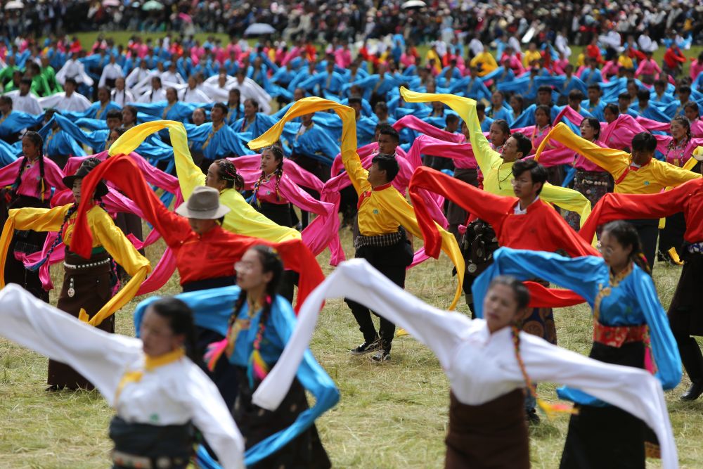 ↑8月12日，身着节日盛装的演员和当地群众在夏泽滩草原上跳起锅庄舞。