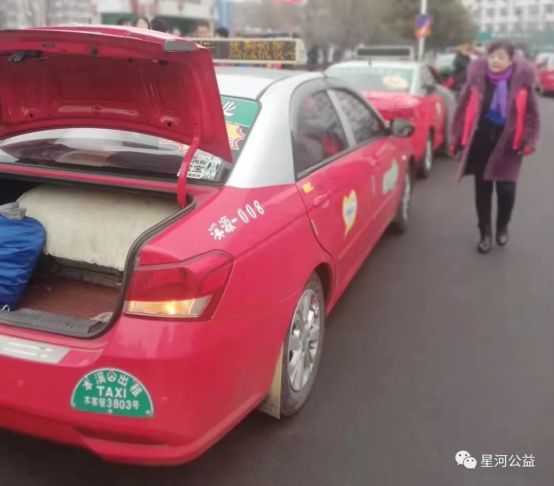 一排贴着郭明义爱心车队本溪溪源同心分队的出租车队在路边整齐停放