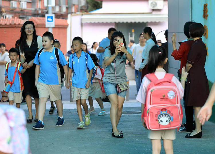 家长给第一天上小学的孩子拍照留念.