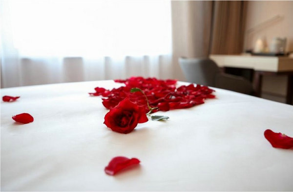 的玫瑰花瓣,蓝牙音箱播放着浪漫的背景音乐,房间里的灯光打得恰到好处