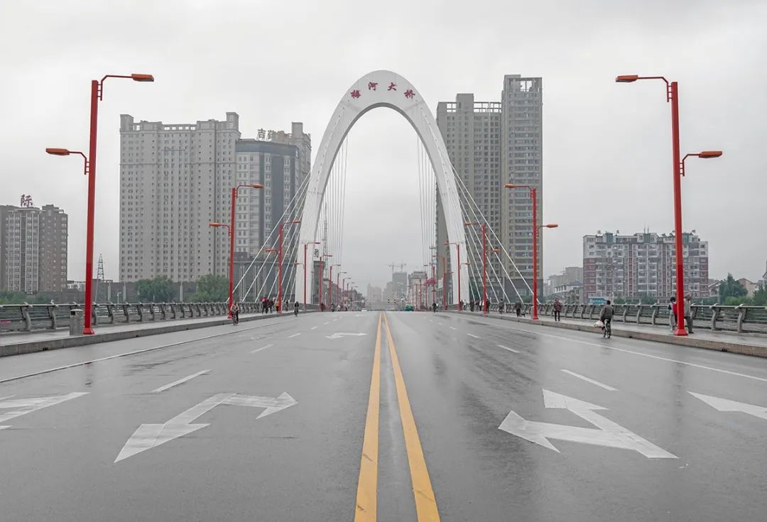 正面拍摄的梅河口大桥行人走在梅河大桥上行人与梅河大桥上的灯柱重叠