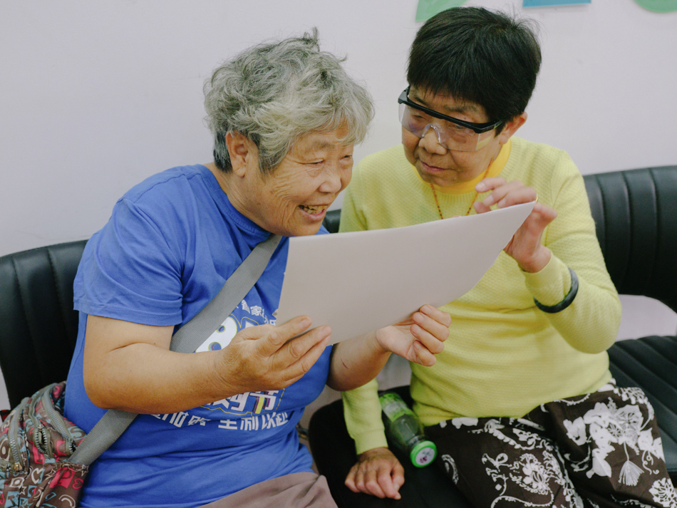 社区老人传阅孩子们制作的拼贴。