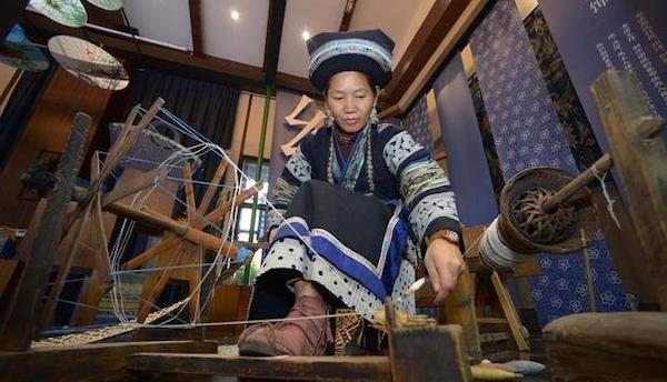 贵州省丹寨县万达小镇非遗展示馆，非遗传承人在展示布依族服饰的制作过程。图片来自新华社
