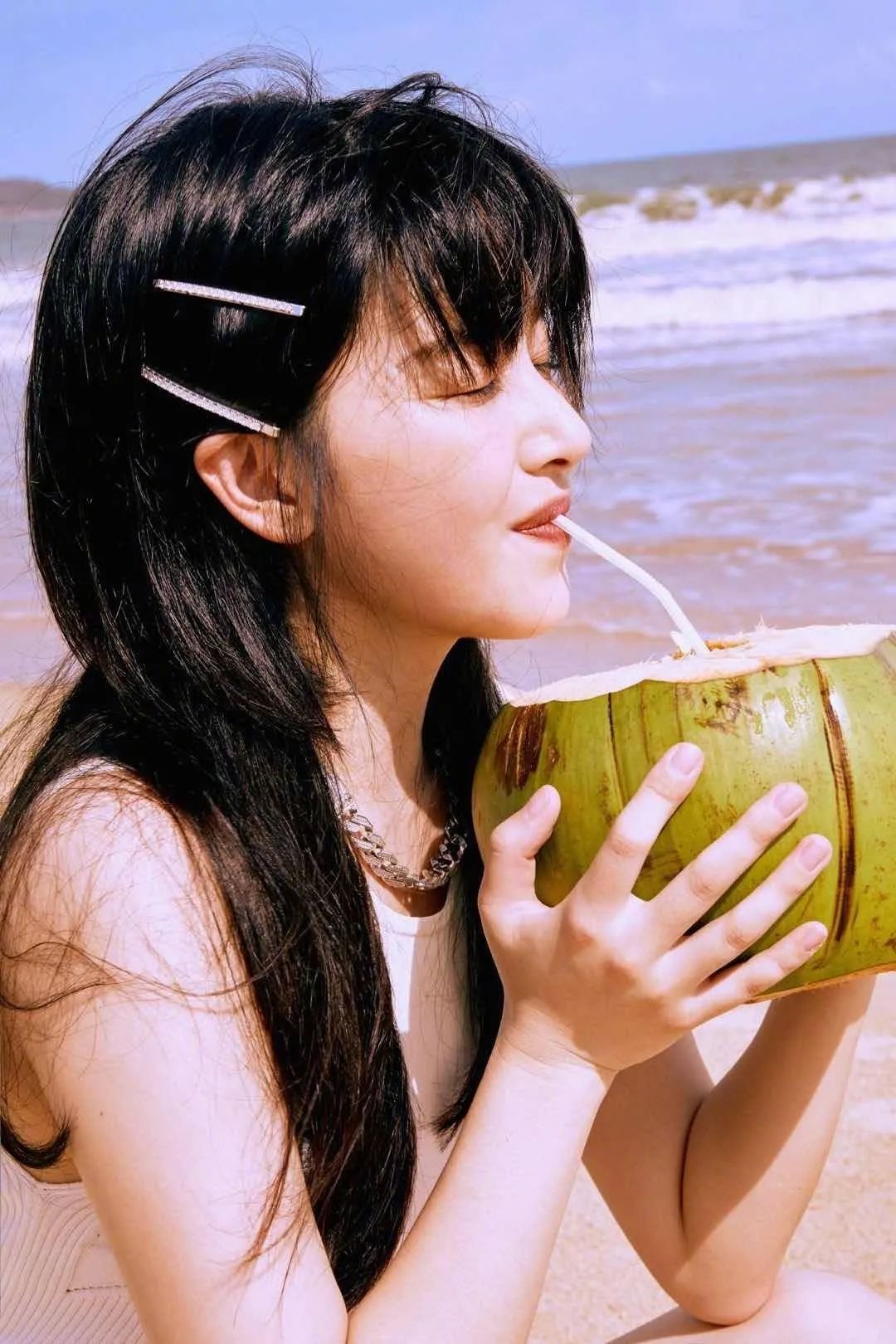 镜头里的清子在沙滩上喝着椰汁,吹着海风,莞尔一笑