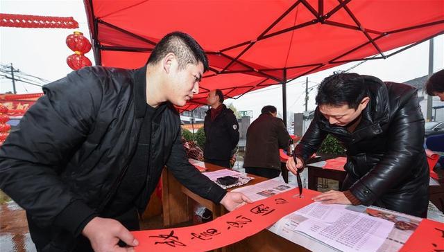 1月4日,在泉庆村民俗文化表演现场,书法爱好者为村民写春联.