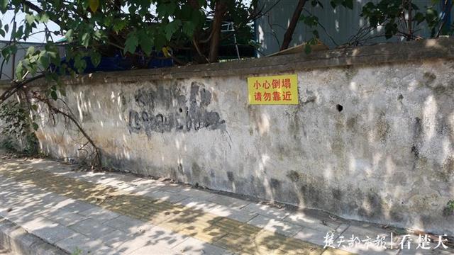 锈迹斑斑,整个墙体存在多处破损的地方,墙面上贴有"院墙危险 请勿靠近