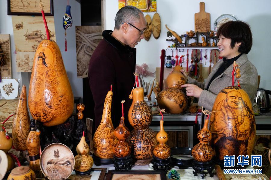 11月28日,在重庆市北碚区“烙艺不绝”烙画工作室,刘光红(右)和丈夫余树元在探讨烙画制作工艺。新华社发(秦廷富 摄)
