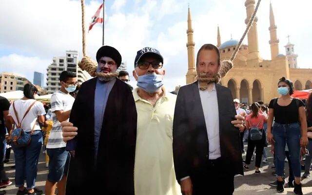（图说：8月8日，贝鲁特烈士广场，抗议者用绞刑绳索“ 吊 ” 着黎巴嫩真主党领袖纳斯鲁拉（左）和前总理巴希尔的画像。图/AFP）