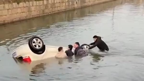 轿车冲入河塘“底朝天”，一群路人跳入水中抬车救人