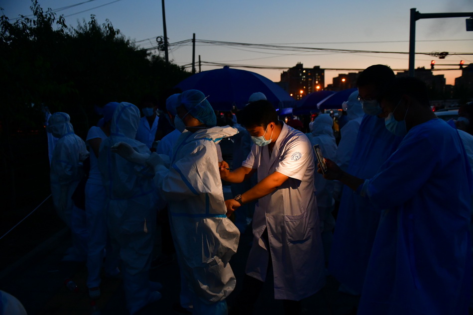 6月15日，夜色下，北京丰台区一处咽拭子样本采集点，工作人员在整理防护服。人民视觉 图